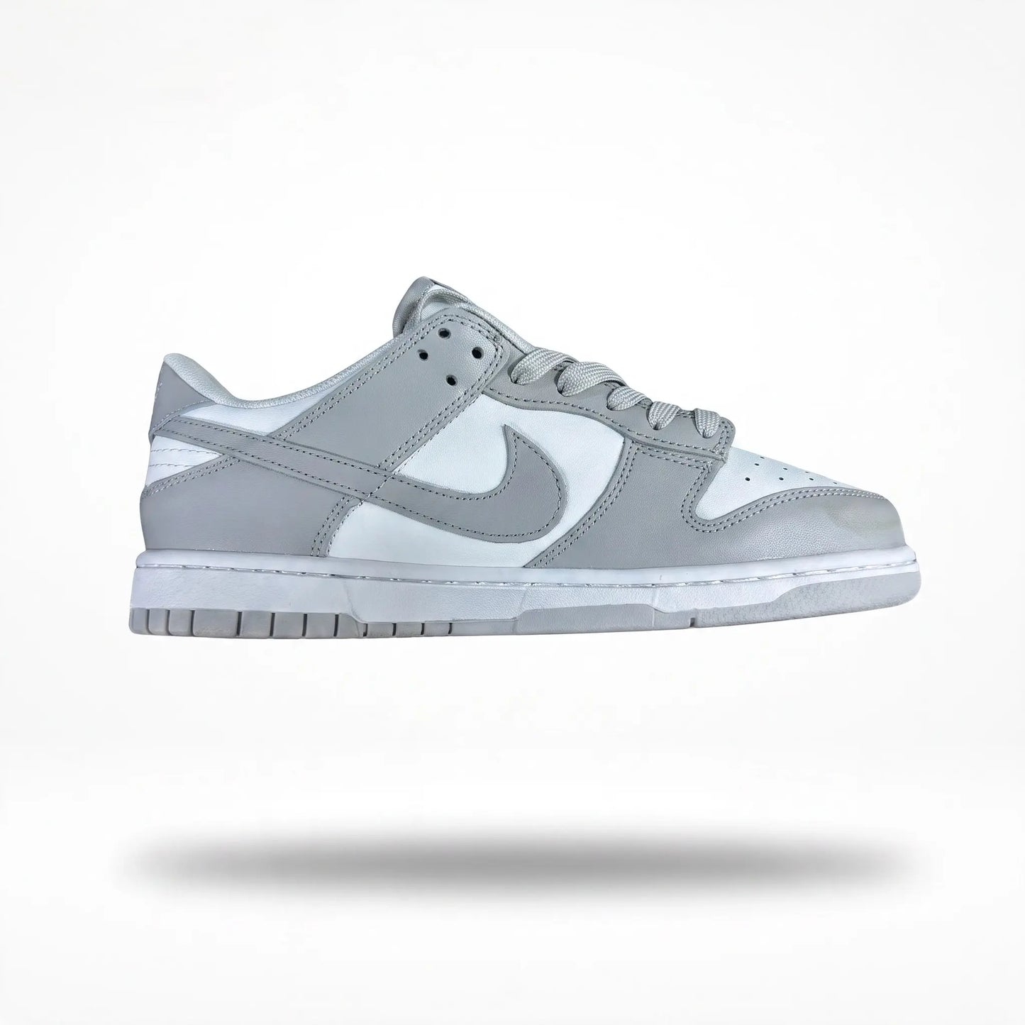 A Nike Dunk sneaker in light gray and white, shown from the side profile against a clean white background with a soft drop shadow.