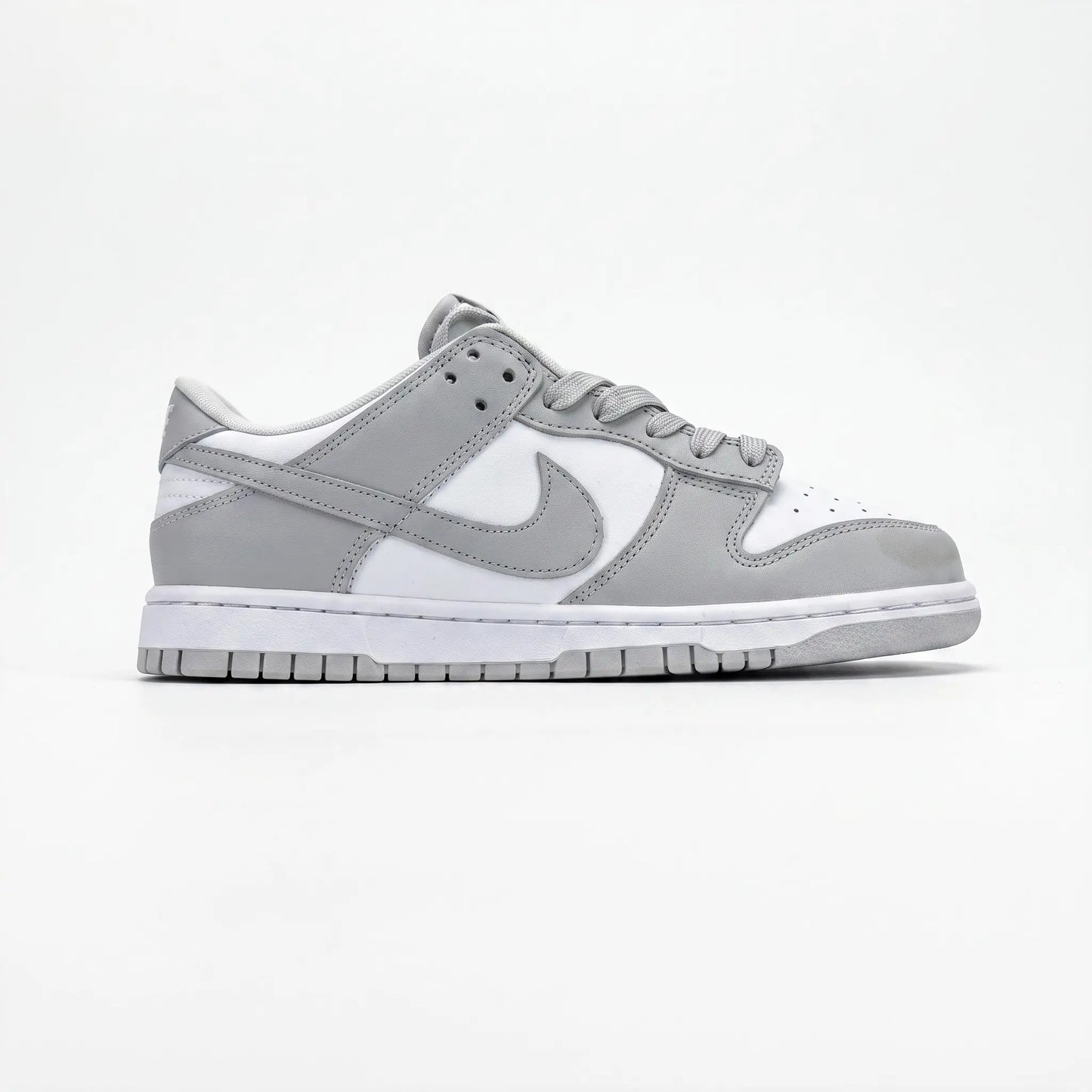 A Nike Dunk sneaker in a light gray and white colorway, shown from the side profile against a clean white background.