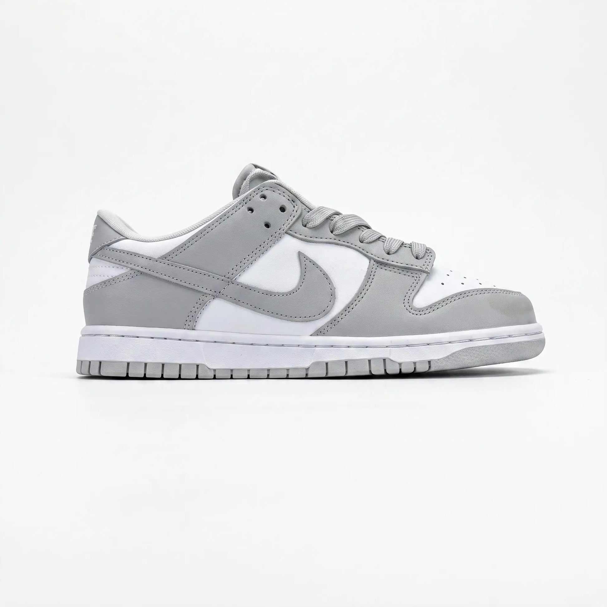 A Nike Dunk sneaker in a light gray and white colorway, shown from the side profile against a clean white background.