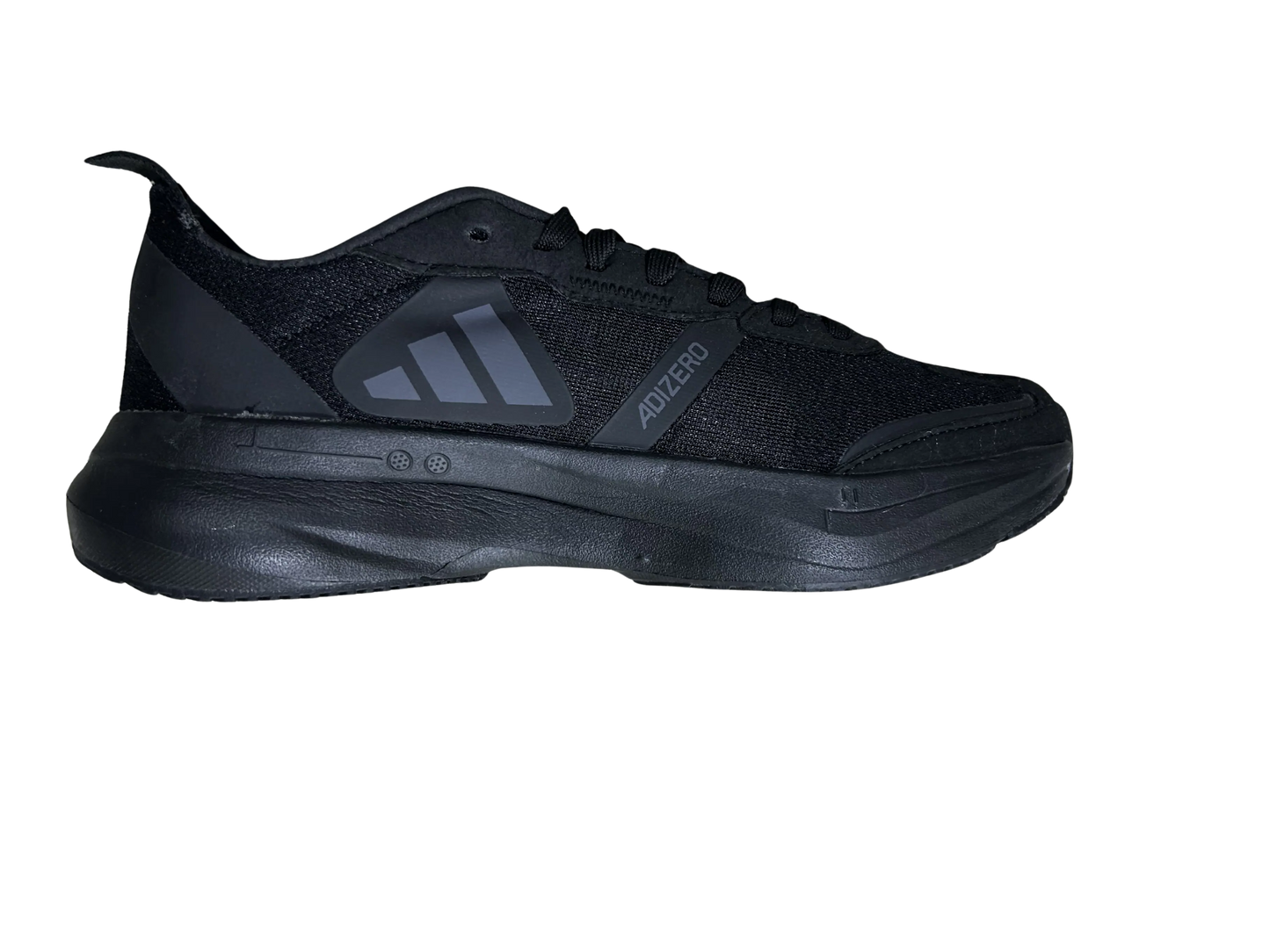 A black athletic sneaker shown in a side profile view against a solid white background, featuring a textured mesh upper, black laces, and a thick black sole with a gray logo accent.