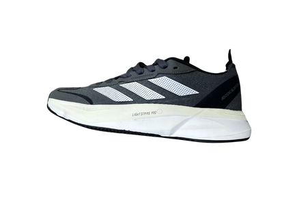 A single Adidas running shoe shown in a side profile view against a plain white background. The shoe features a dark gray mesh upper with three white stripes, a thick white midsole, and black accents.