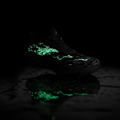 A dark athletic shoe with glowing neon green graphic details, photographed on a wet reflective black surface against a black background.