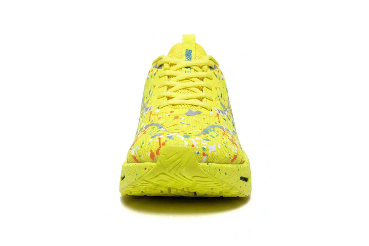 A bright yellow athletic sneaker with a colorful paint splatter pattern on the upper, shown from a front-facing perspective on a white background.