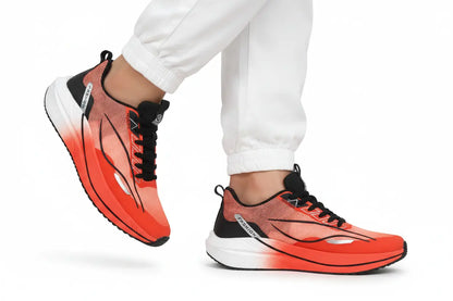 A pair of athletic sneakers in a vibrant red and orange gradient with black accents, shown on a model wearing white joggers against a white studio background.